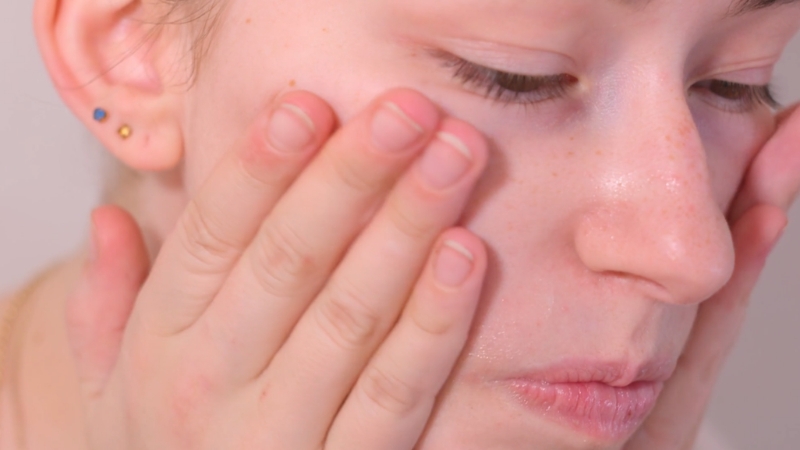 Žena rukama nanosi serum na lice